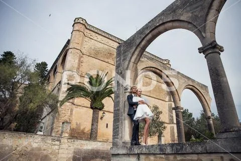 Fashionable wedding couple near Catholic church. Outdoor portrait Stock Photos