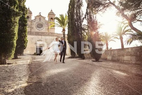 Fashionable wedding couple near Catholic church. Outdoor portrait Stock Photos