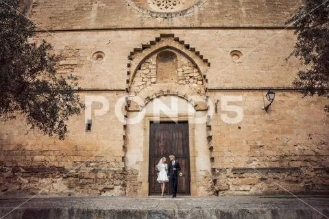 Fashionable wedding couple near Catholic church. Outdoor portrait Stock Photos