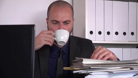 Fashionable young business man indoors checking paperwork stack drinking coffee Stock Footage