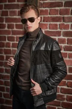 Fashionable young man in black leather jacket stands in loft apartments. Men' Stock Photos