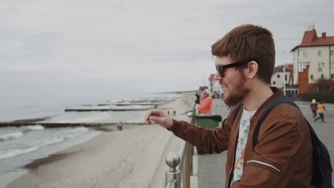 A fashionable young man with a red beard, in a brown leather jacket, wearing Stock Footage 75572003