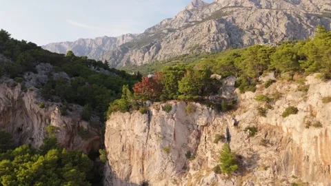 Fast Aerial Pull-Back Drone Shot with Parallax Effect: Cliff, Sea, and Mountains Stock Footage 320145926
