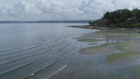 Fast aerial pull out of the waves of Dumas Bay revealing more of the scene with Stock Footage 304637491