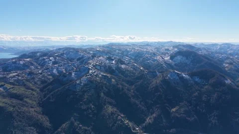 Fast Aerial Pullback From Snowy Forest Mountains Toward Blue Sea Stock Footage 342841052