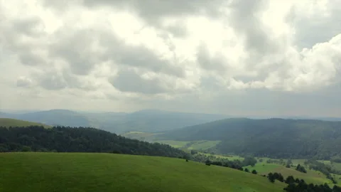 Fast aerial push in panorama of rolling green hills, meadows and forested Stock Footage 320595538