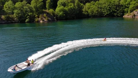 Fast boat towing an inflatable ring in a fjord Stockbeeldmateriaal 273251396