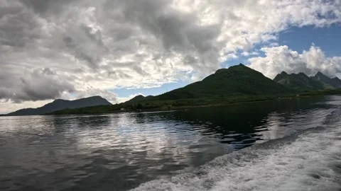 Fast boat wake on right side passing green hills and cloudy sky in Lofoten Видео 344753110
