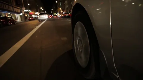 Fast car parallel parking close up side shot mounted to tire at night time Stock Footage 75736422