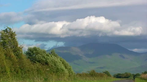 Fast clouds driven by wind over mountain, grass in foreground Stock Footage 39987378