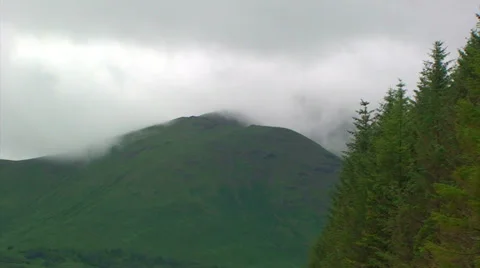 Fast clouds over a mountain top and spruce forest in Highlands Stock Footage 39815397
