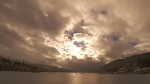 Fast clouds rush over Scottish highland loch, shafts of light Stock Footage 313637954