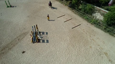 Fast drone flyover of arena as trainer watches riders jumping improvements Stock Footage 315479904