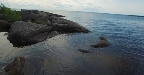 Fast flight above bare rocks on lake bank under overcast sky Stock Footage 100982341
