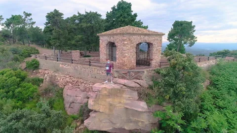 Fast flight of drone towards man with mask on top of stones and hermitage Stock Footage 138896112