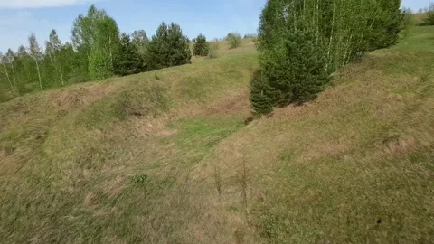 Fast flight low above the ground. View of hills and trees. No one around, sunny  Stock Footage 274405099