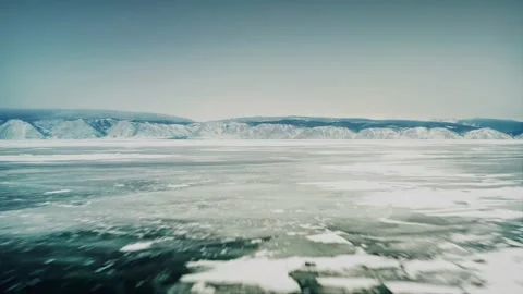 Fast flight over the ice of Lake Baikal, with a mountain range in the background Stock Footage 228826161