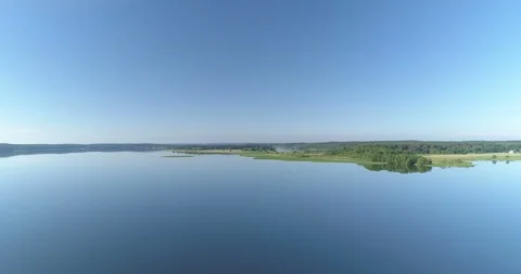 Fast flight over idyllic lake with glass calm surface green forest and blue Vídeo Stock 90954082