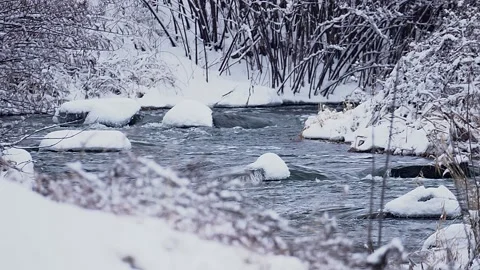 The fast flow of a winter river among snow-covered rocks and banks, Stock Footage 327865886