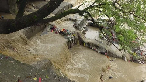 Fast flowing brown river water rushing down concrete steps high-angle view Vídeo Stock 342586789