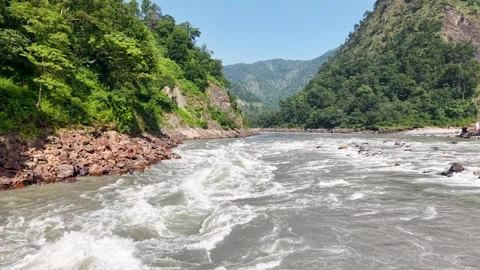 Fast flowing mountain river rapids rushing between lush green valley Vidéo 347764061