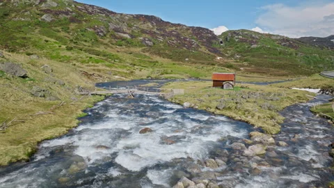 A fast-flowing mountain river runs through a wide Norwegian valley. Stock Footage 328131245