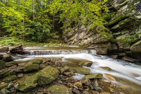 Fast flowing river stream with smooth silky water falling from big stones in Stock Photos