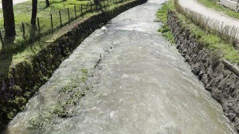 Fast flowing river stream with stone embankments on a sunny day Stock Footage 340079622