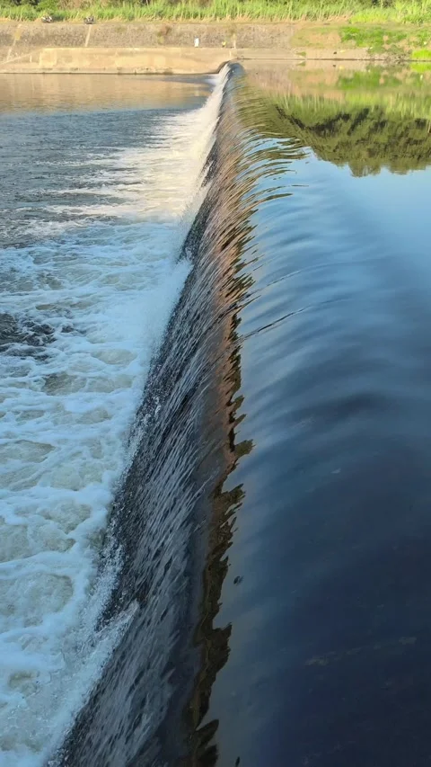 Fast-Flowing River Water Cascading Over a Small Weir Stock Footage 341536393