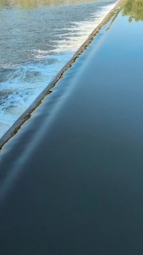 Fast-Flowing River Water Cascading Over a Small Weir Stock Footage 341536407