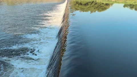 Fast-Flowing River Water Cascading Over a Small Weir Stock Footage 341536408
