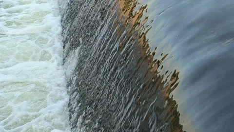 Fast-Flowing River Water Cascading Over a Small Weir Stock Footage 341536595