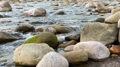Fast flowing stream water passing stones and boulders on shallow river creek Video stock 345172154