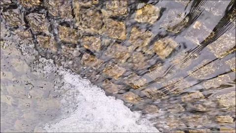 Fast flowing water stream over textured cobblestone pattern Video stock 345097488