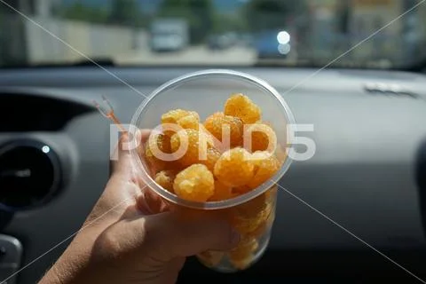 Fast food in the journey - yellow raspberry in a plastic Cup. Stock Photos
