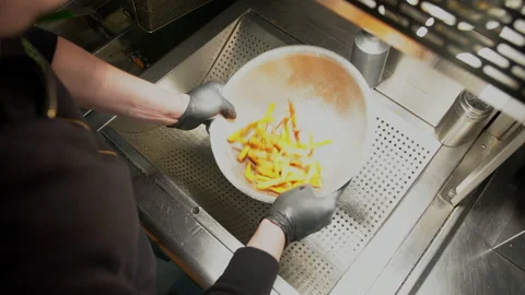 Fast food worker making a serving of french fries. Overhead view of fast food Stock Footage 149318530