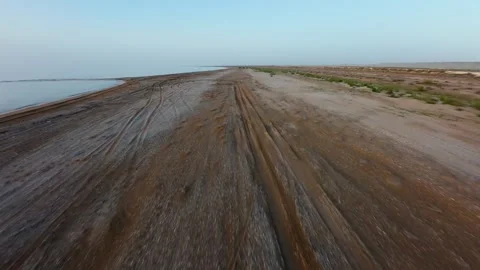 Fast forward flight over coastal sandy terrain with tire tracks Stock Footage 344418646