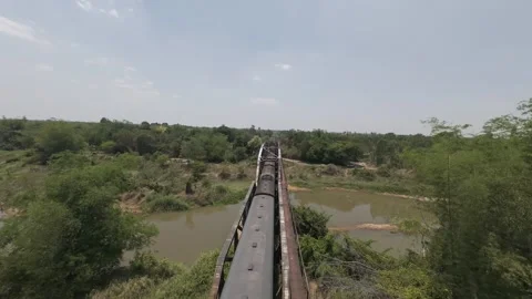 Fast FPV flight pulling away from a passenger train across a old railroad Stock Footage 335923414