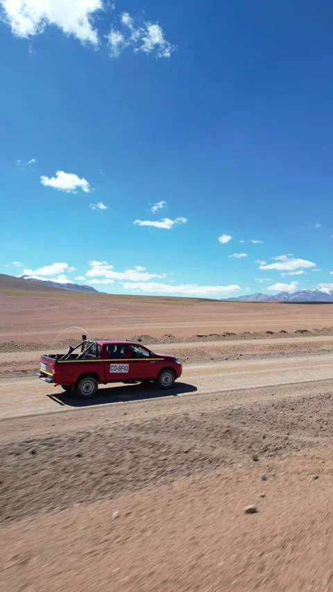 Fast low aerial pass alongside a red pickup truck speeding along a remote Stock Footage 340551268