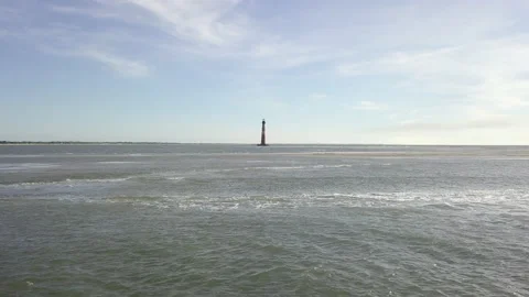 Fast low flight over ocean toward lighthouse Stock Footage 138072946