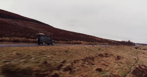 Fast low tracking shot of Land Rover Defender on mountain road drone aerial 4K Stock Footage 104586103