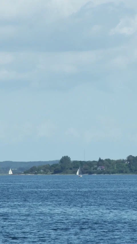 Fast-motion vertical footage showing white sailboats gliding across the sea 動画素材 334052170