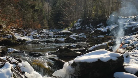 Fast mountain river and bonfire near snow covered forest Stock Footage 301366071