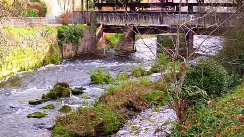 A fast mountain river flows among the stones. On one side, there is a stone wall Stock Footage 299067174