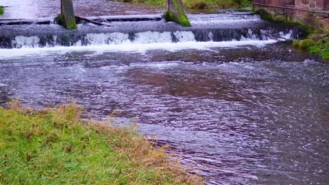 A fast mountain river flows among the stones. On one side, there is a stone wall Stock Footage 299076886