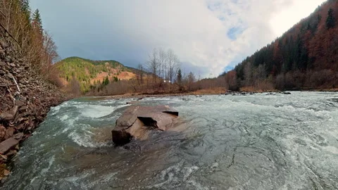 Fast mountain river flows through a broad autumn valley surrounded by forest 動画素材 343382622