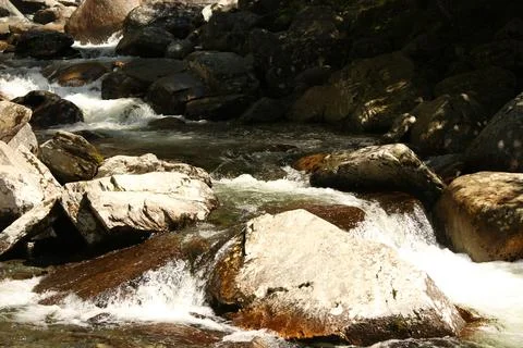 Fast mountain stream flowing through large stones and rocks Stock Photos