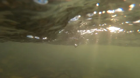 Fast movement of water with moving rays of sun on surface of water and in water. Stock Footage 141686596