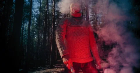 Fast moving camera towards a man waving a signal flare in the woods Stock-Footage 77545104