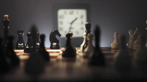 Fast moving chess pieces in dark environment with white clock in background Stock Footage 312812563